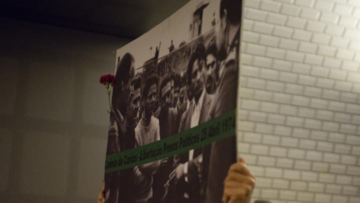 Um popular mostrando um cartaz evocativo da libertação dos presos políticos da Cadeia de Caxias